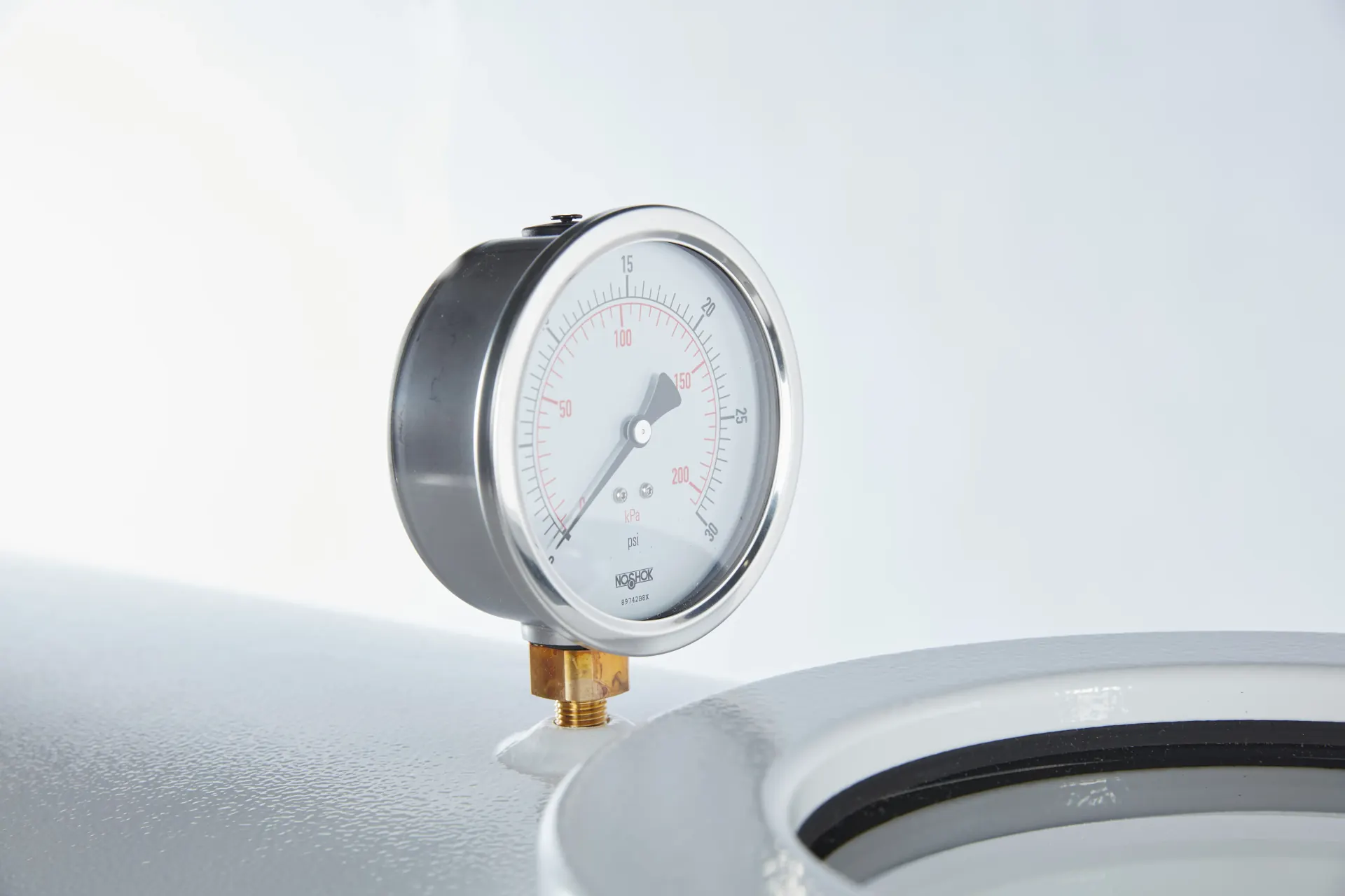 Brass fitted pressure gauge on top of an OxyHealth hard shell chamber