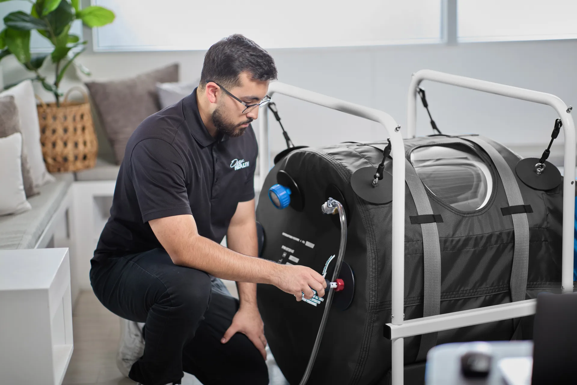 Man with OxyHealth Quamvis 320 black hyperbaric chamber in professional lifestyle setting